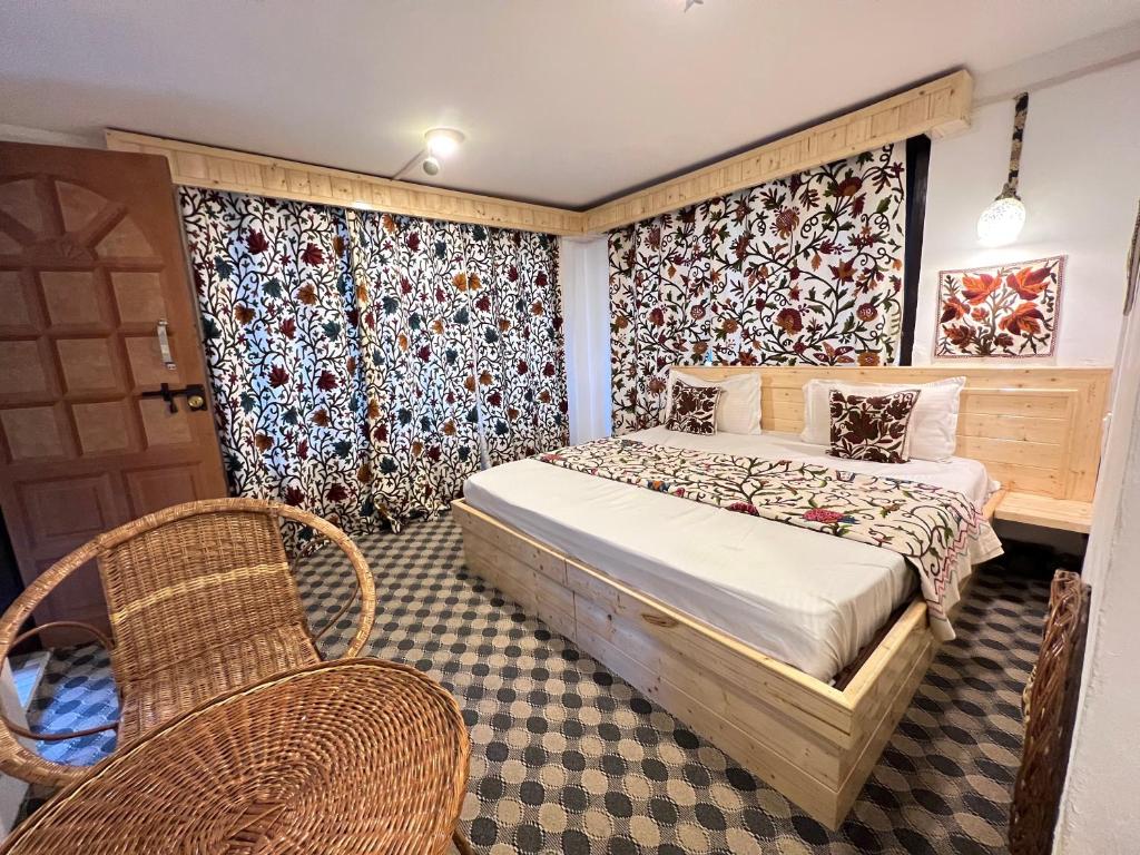a bedroom with a bed and two chairs and a door at The AISHANA PAHALGAM in Pahalgām