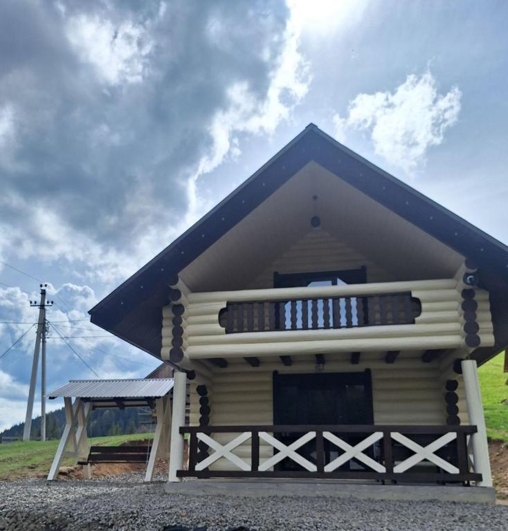 a small house with a blue roof and a balcony at Тихий світанок in Synevyrsʼka Polyana
