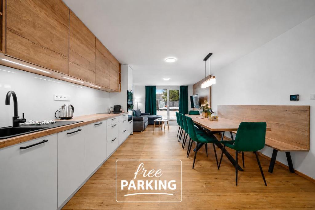 a kitchen and dining room with a table and green chairs at Apartmány Rezidence Lyžařská in Janske Lazne