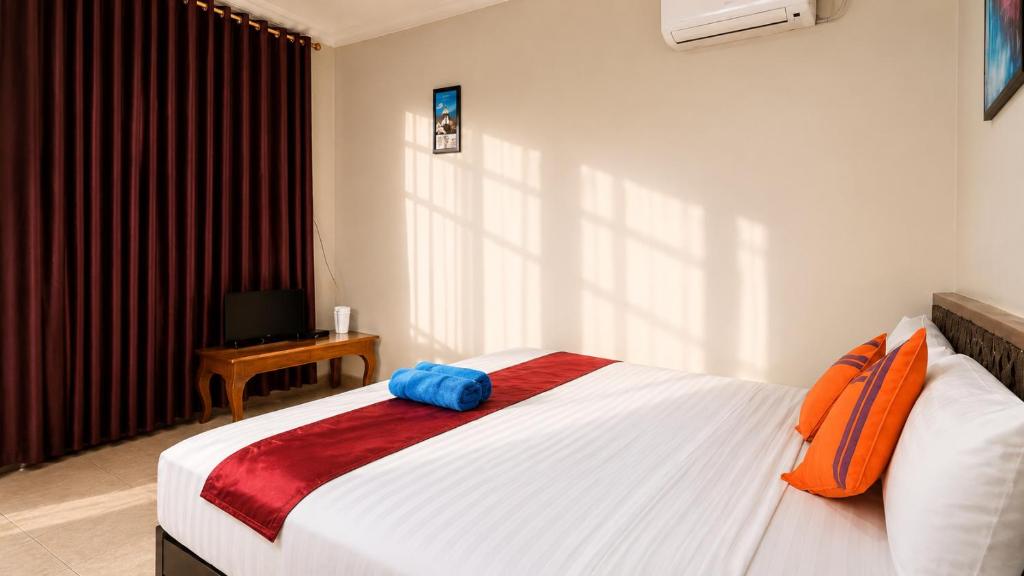 a bedroom with a bed with an orange bag on it at Cahaya Adrian Hotel in Labuan Bajo