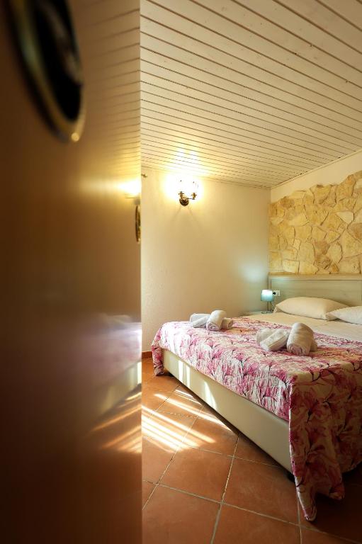 a bedroom with a bed and a stone wall at VILLA MARIA ELENA Charme Rooms sul mare in Capo Vaticano