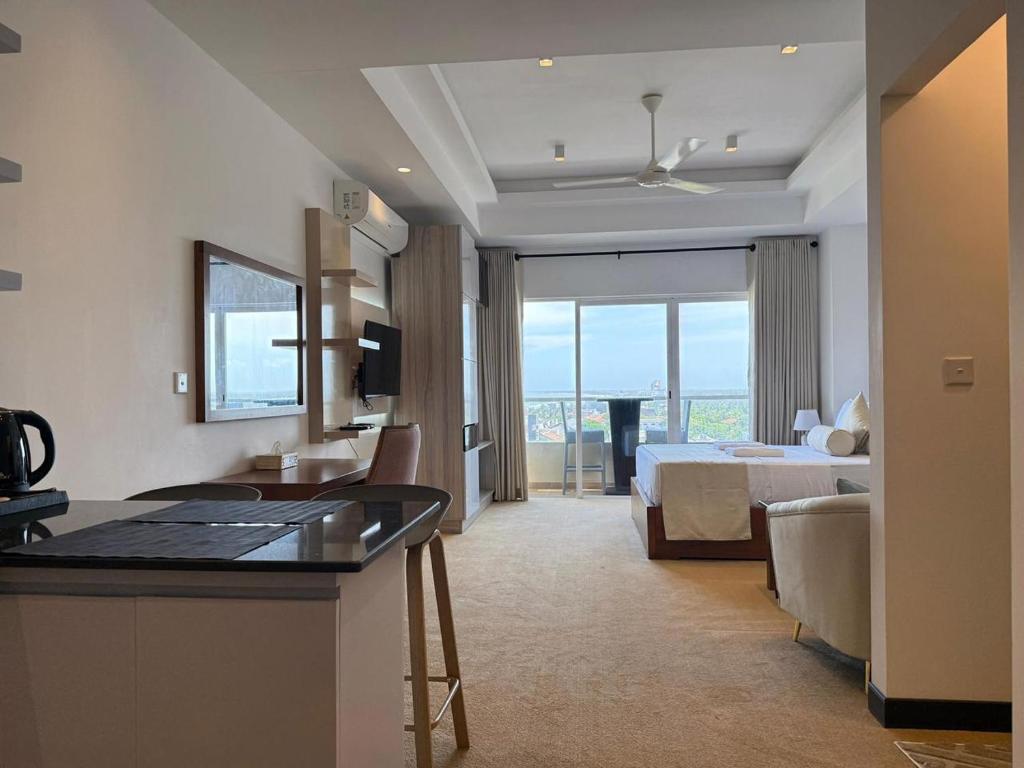 a hotel room with a bed and a bedroom with a view at Ocean Breeze Residencies in Negombo