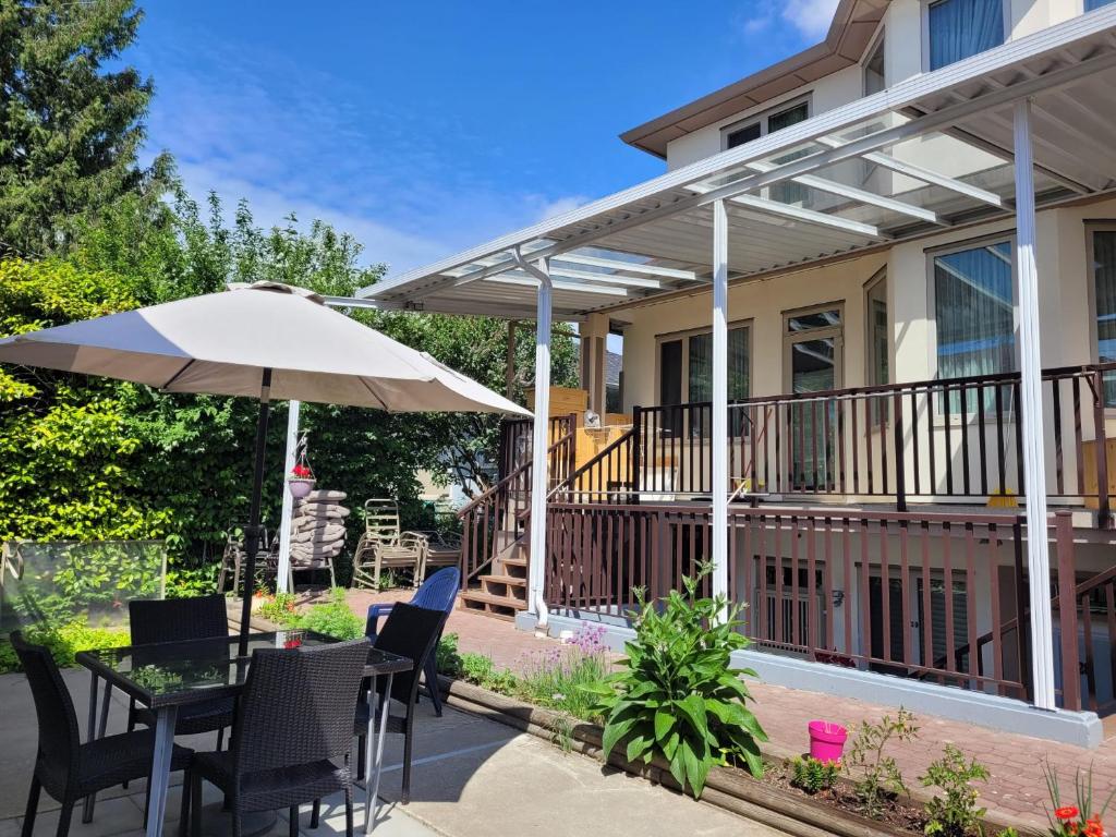 a patio with a table and an umbrella at Private Room in Guest House, Near the New Oakridge Mall & Transit - Near Langara 49th Station in Vancouver