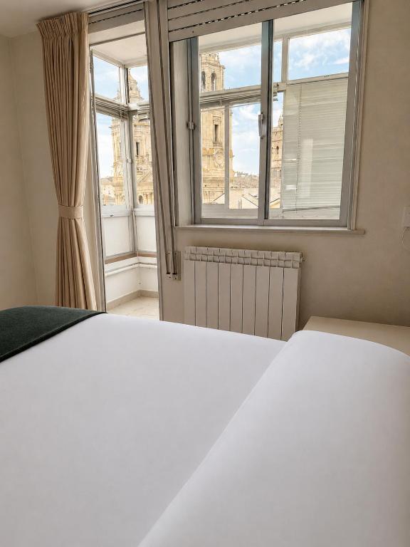 a bedroom with a white bed and a window at Hostal Porta Santiago in Lugo