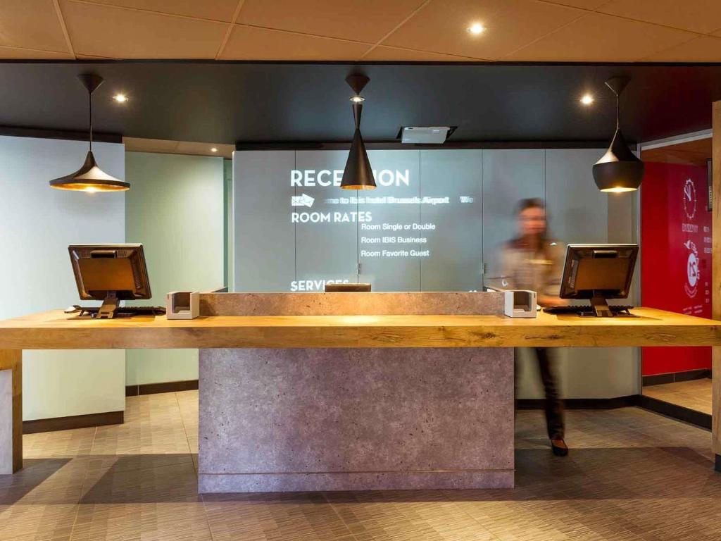 a reception desk with two computers on top of it at ibis Hotel Brussels Airport in Diegem