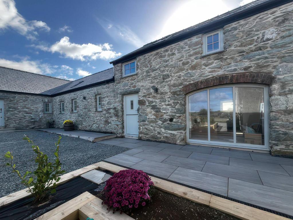 a stone house with a patio in front of it at Storws Tanrallt in Holyhead