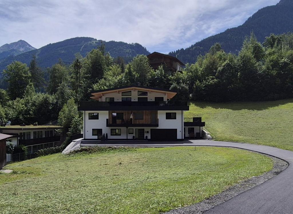 a house sitting on top of a lush green field at Mountainsurf Apartments in Finkenberg
