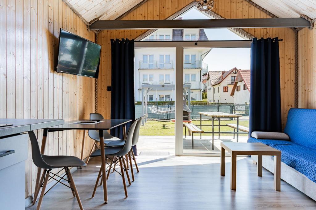 a living room with a table and chairs and a couch at Domki Anchor II - 200m od Morza, Klimatyzacja, Plac Zabaw, Parking in Karwia