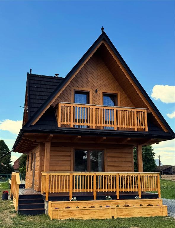 a log cabin with a porch and a balcony at Domek Pod Tatrami - Koniówka, blisko Term Chochołowskich in Koniówka