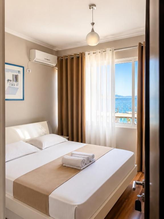 a bedroom with a large white bed with a window at British Hotel in Himare