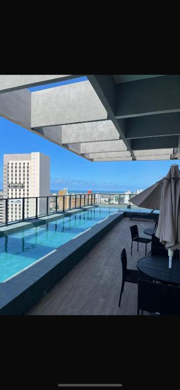 a balcony with tables and chairs and a swimming pool at Apartamento Max Derby Boulevard in Recife