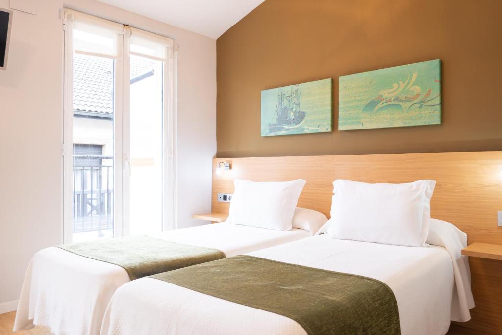 two beds sitting next to each other in a room at Hotel Olatu in Zarautz