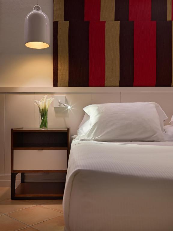 a bedroom with a white bed and a nightstand with a flower on it at H10 Playa Esmeralda - Adults Only in Costa Calma