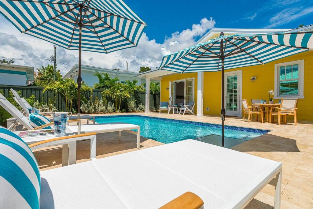 a villa with a swimming pool with tables and umbrellas at The Luxe Sunshine Villa w Private Pool House in West Palm Beach
