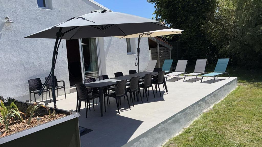 a patio with a table and chairs and an umbrella at L'îlo'T in Ker Pierre Borny