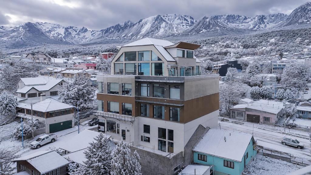 a large building with snow covered mountains in the background at Patagonia Home in Ushuaia