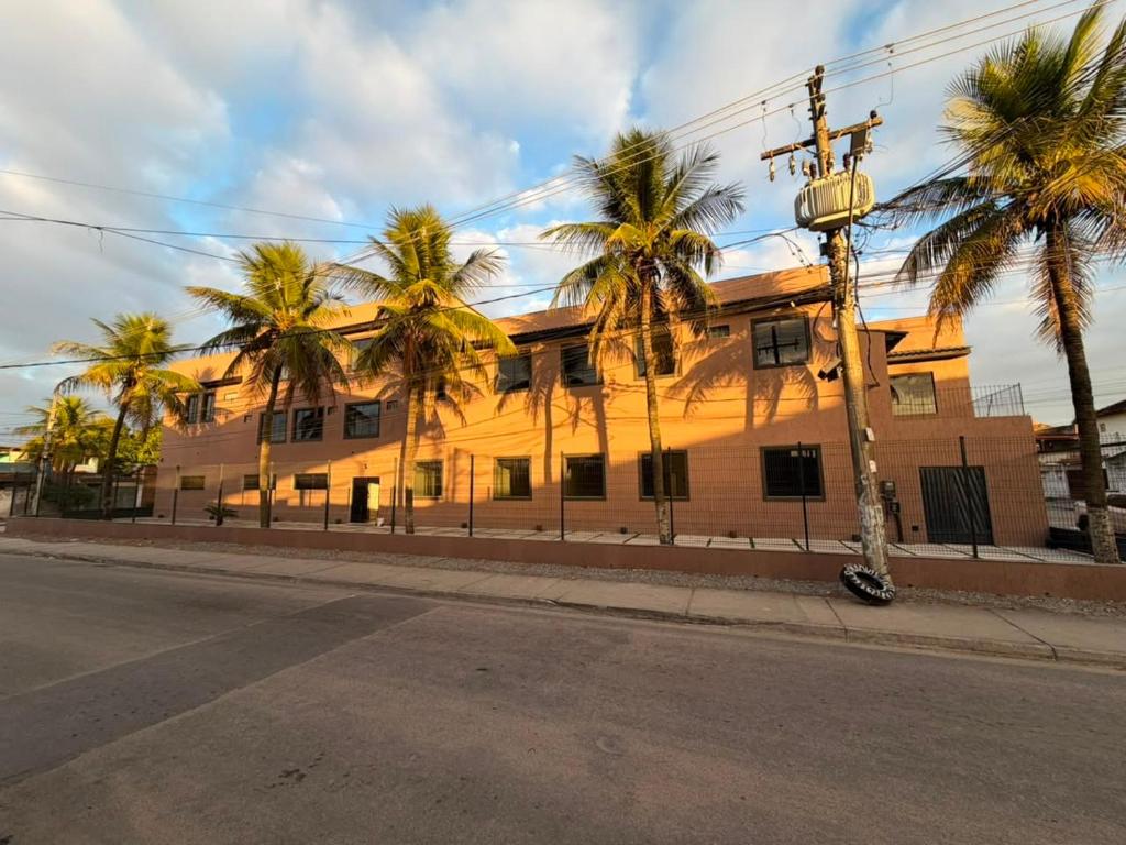 a building with palm trees in front of a street at Hotel Betel 3 pontes in Itaboraí