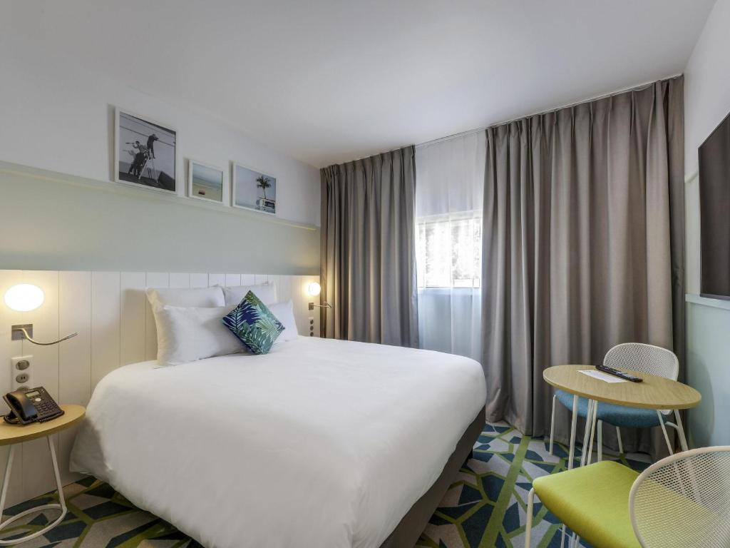 a hotel room with a large white bed and chairs at Mercure Paris Orly Airport in Orly