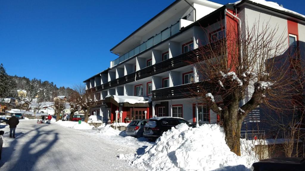 ein Gebäude mit einem Baum im Schnee neben einer Straße in der Unterkunft Hotel Thier in Mönichkirchen