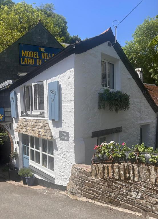 a white building with a sign that reads the model will land up at Forge Cottage in Polperro