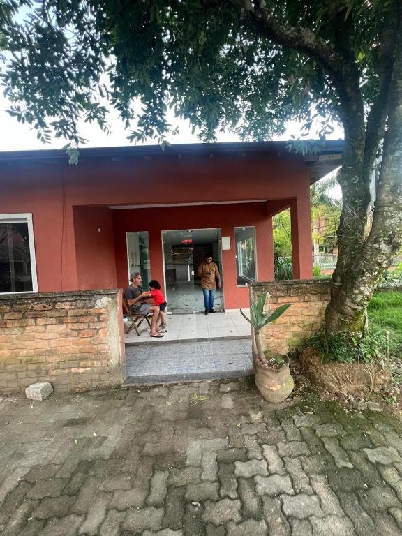 a group of people sitting outside of a red house at Hotel Betel Rio Bonito in Estaçao Realengo