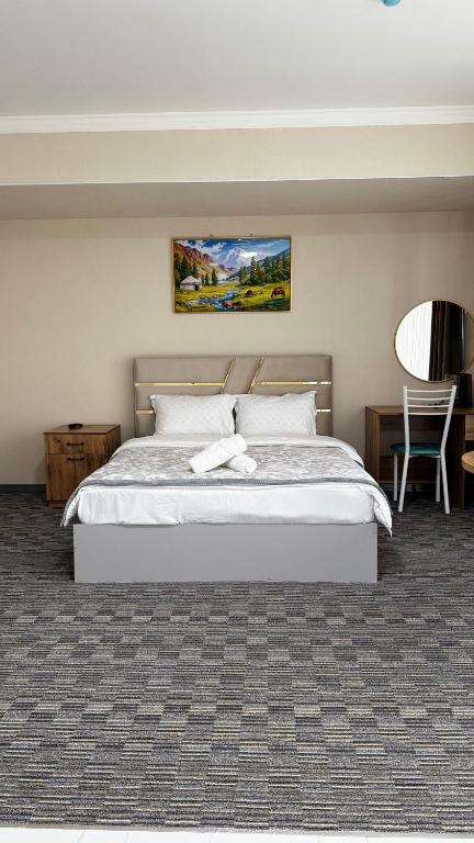 a bedroom with a bed and a table and a chair at Kyialym Hotel in Bishkek
