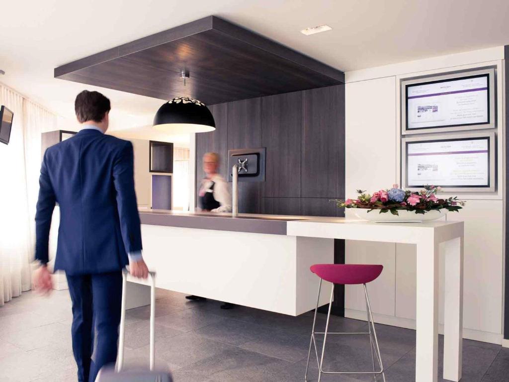 a man in a suit walking into a kitchen at Mercure Hotel Nijmegen Centre in Nijmegen
