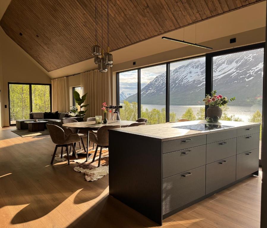 a kitchen and dining room with a table and mountains at LyNora - A private fjord retreat in Indre Ravelseidet