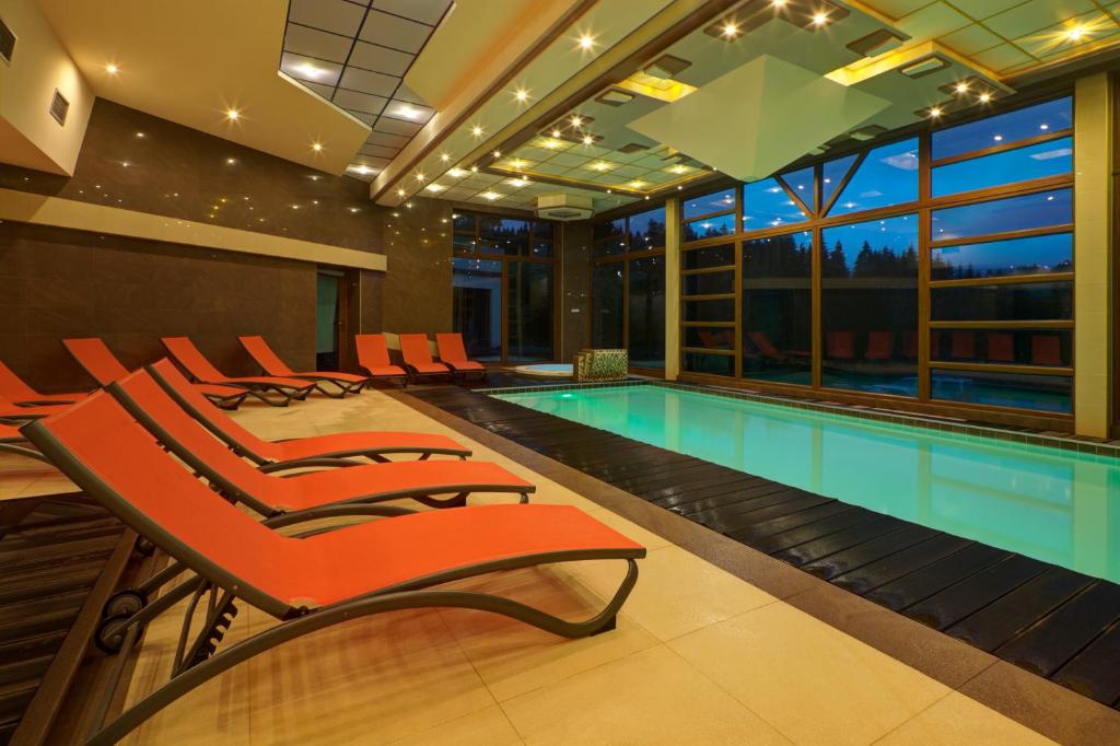 a swimming pool with orange chairs next to a swimming pool at Holiday Park Orava - Hotel Orava in Dolný Kubín