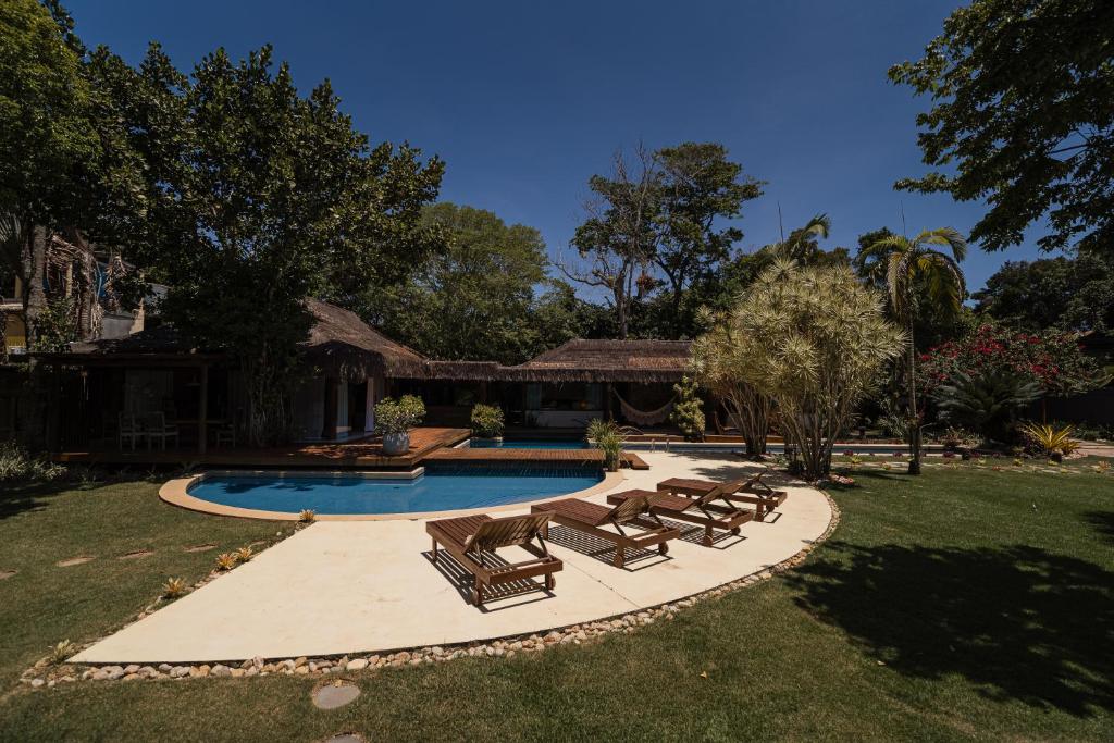 a swimming pool with lounge chairs and a house at Villa Cozy - Pousada Boutique in Arraial d'Ajuda