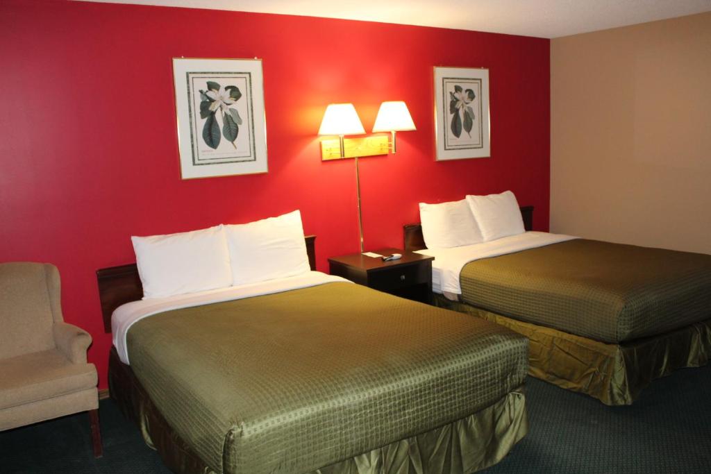 two beds in a hotel room with red walls at Colonial Inn in Dyersville