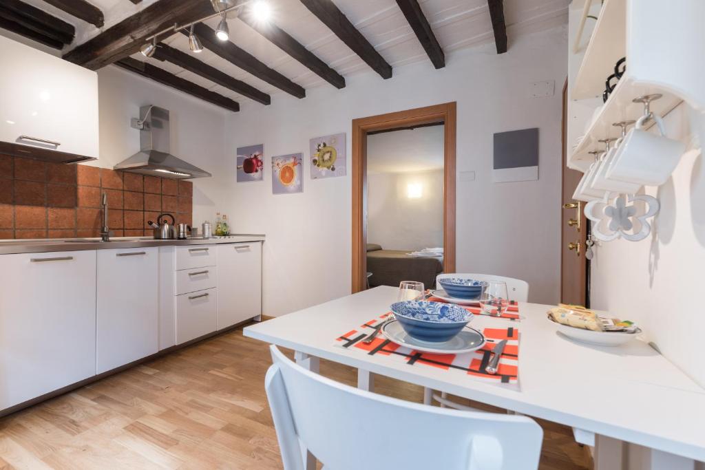 una cocina con armarios blancos y una mesa con sillas. en Roommo Carmine, en Florencia