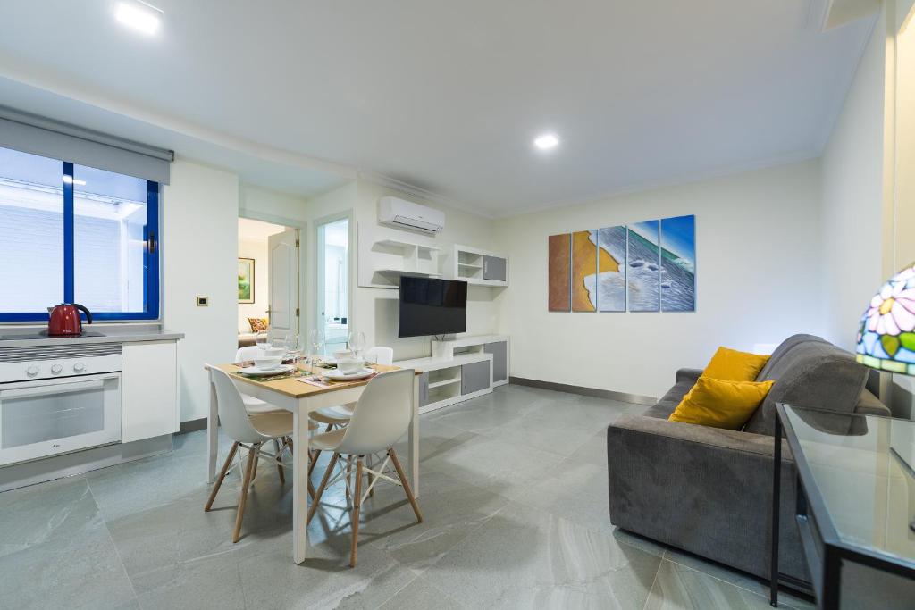 a living room with a couch and a table with chairs at Suites Garden Apartamento 16 in Las Palmas de Gran Canaria