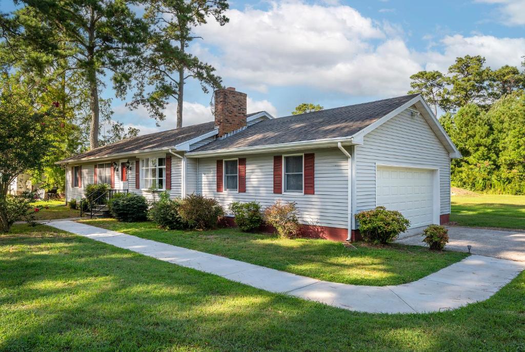 a white house with a chimney and a driveway at Happy Pines in Chincoteague