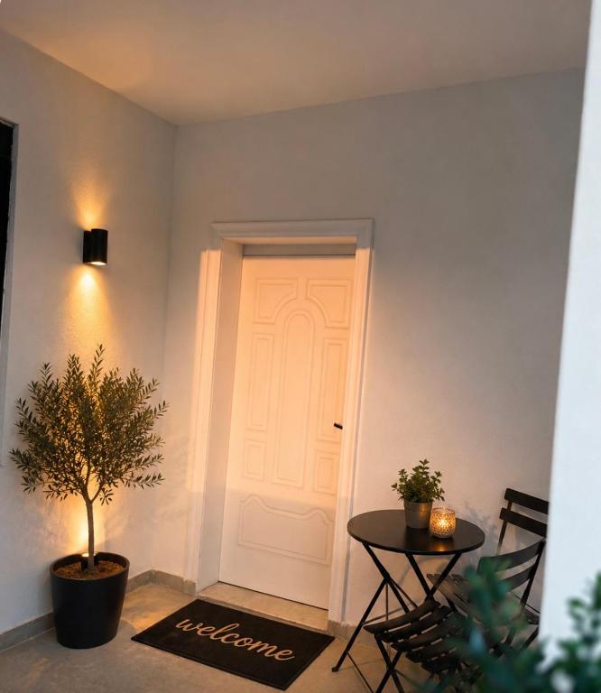a white door in a room with a table and a plant at Guest House by Roni in Durrës