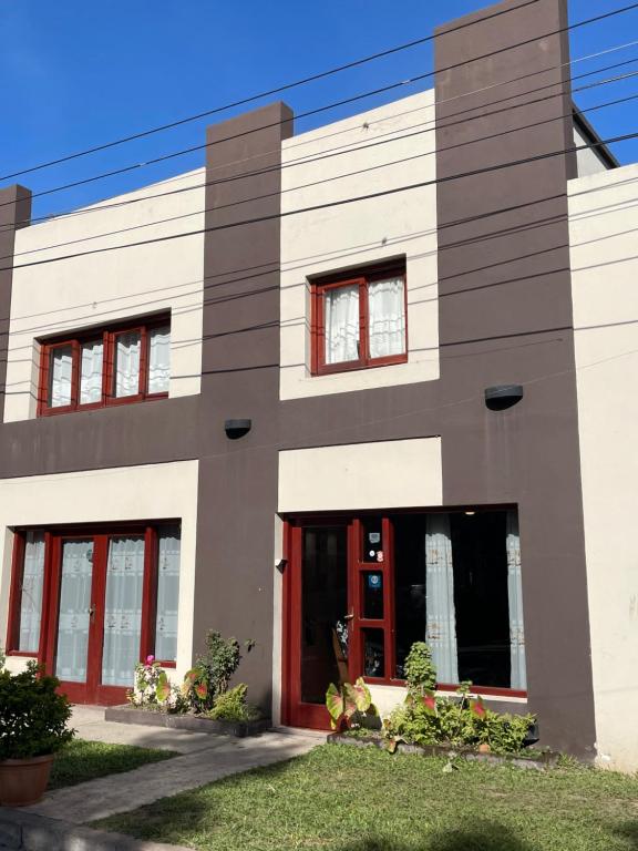 a white building with red doors and windows at Benitez Hostería in Calilegua
