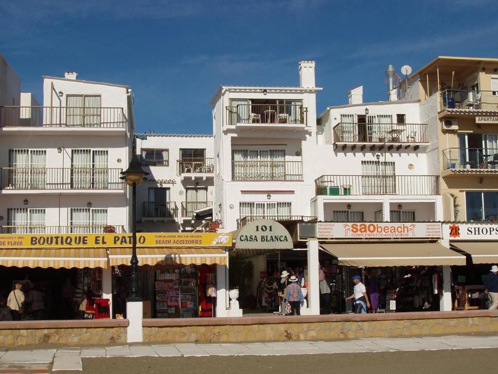 un gran edificio blanco con tiendas enfrente en Apartamentos Casa Blanca, en Torremolinos