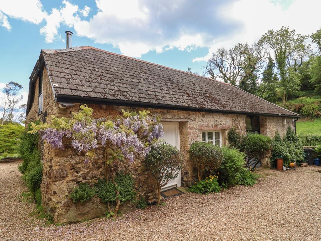 a stone house with flowers on the side of it at Pottery Barn in Branscombe