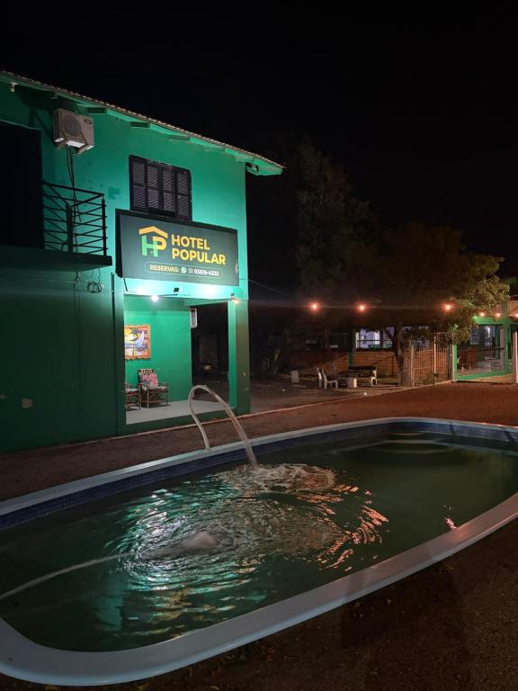a swimming pool in front of a hotel at night at Hotel Popular in Pântano Grande