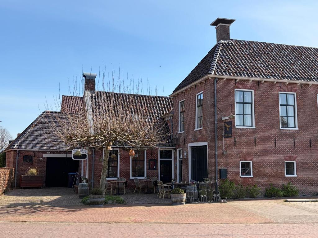 a large brick building with a tree in front of it at Herberg In de Valk in Middelstum