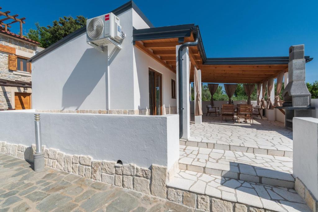 a white house with a stone wall and a security camera at House Guesthouse Stipe in Lopar
