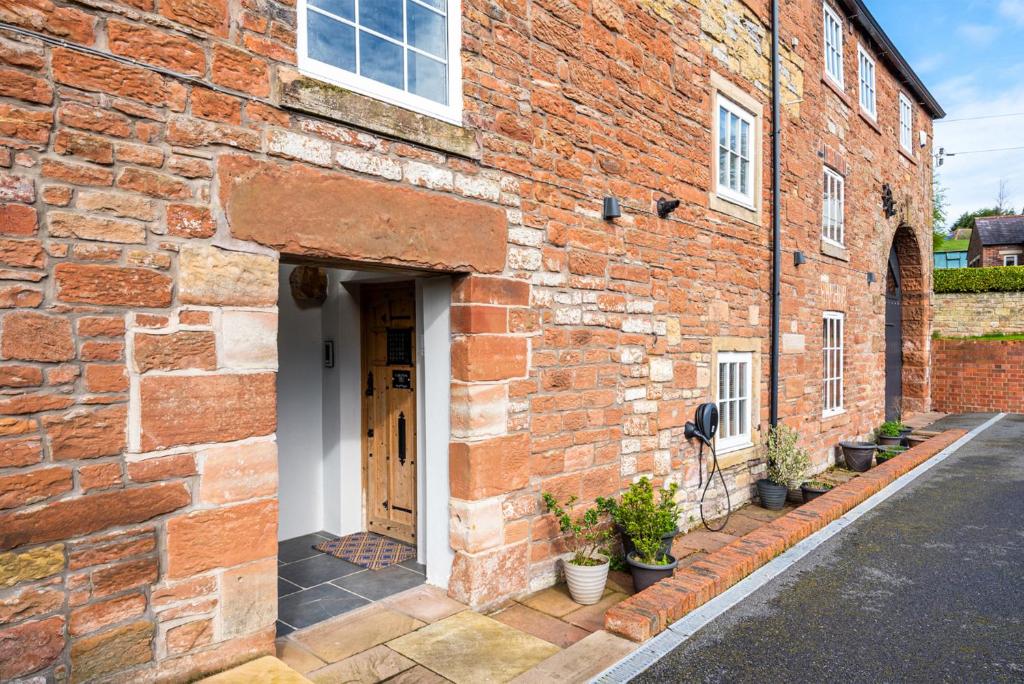 a brick building with a door and some plants at Carleton Mill Cottage in Carlisle