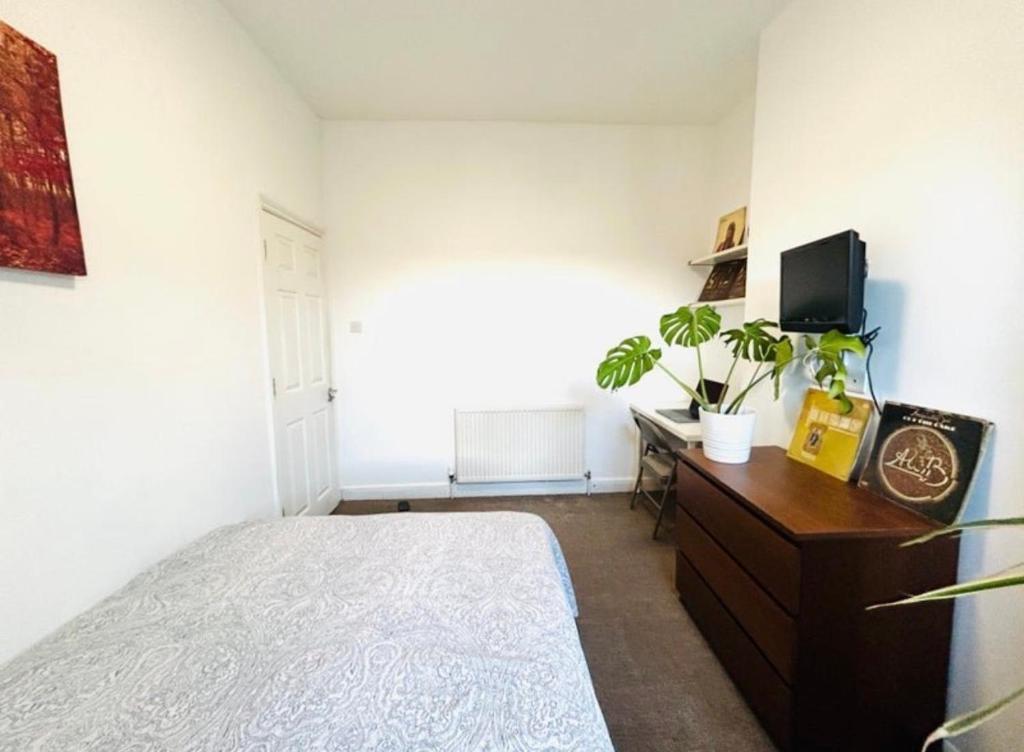 a bedroom with a bed and a dresser with a tv at Home Vibes in Hornchurch