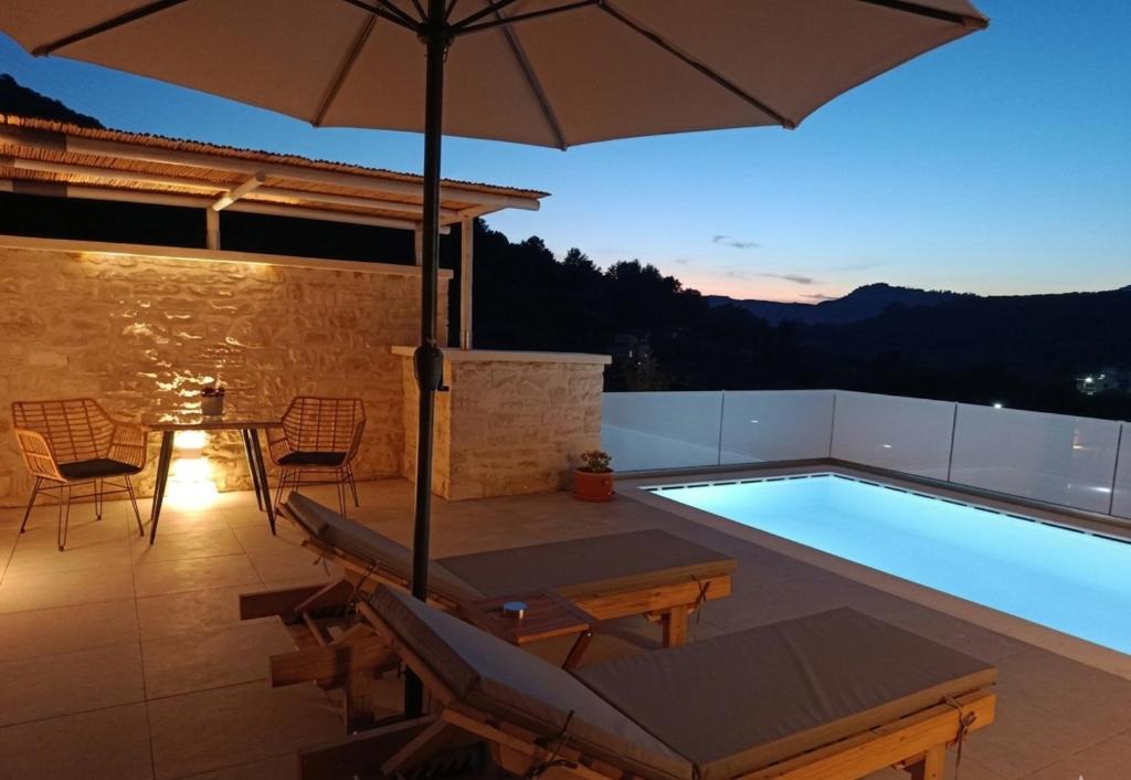 a swimming pool with a table and an umbrella at Lux Studios With Private Pool by ILIOS Georgioupoli in Georgioupoli