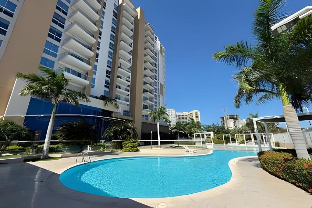 a swimming pool in front of a building with palm trees at Ocean Club by Colproperty Management in Playa Bello Horizonte