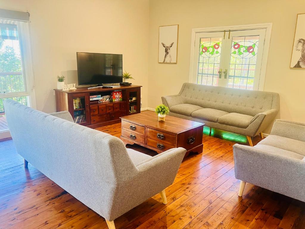 a living room with two couches and a tv at Treetops Escape Albury in Albury