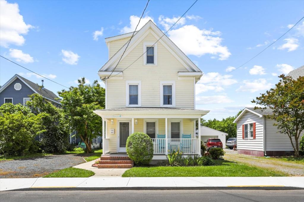 a white house with a porch on a street at Precious Time in Chincoteague