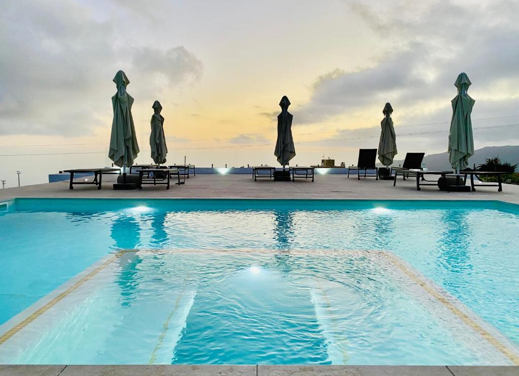 a swimming pool with umbrellas and tables and chairs at Loft Los Laureles in El Paso