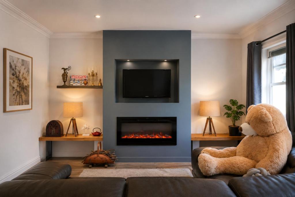 a teddy bear sitting on a couch in a living room with a fireplace at White House Bendigo Garden Retreat in Epsom