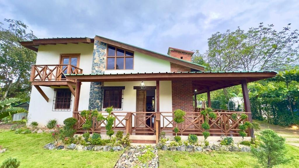 a house with a wrap around porch with a deck at Villa Ana Rosa in Jarabacoa